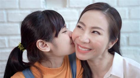 asian teenage daughter kissing mother showing love between mother and