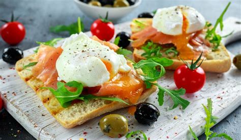 gestroopt ei op geroosterde toost met gerookte zalm rucola olijven en groenten op witte raad