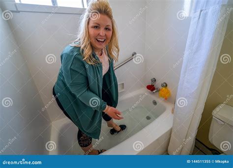 Woman Stands In A Bathtub And Washes Her Feet And Her Shoes With A Big