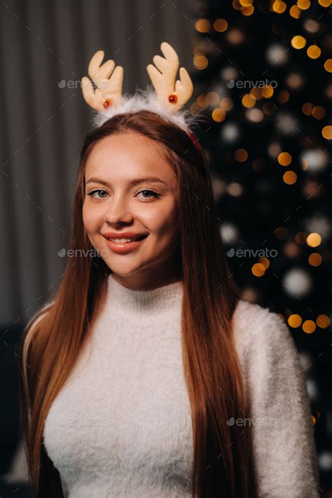 Girl For Christmas With Reindeer Horns In The Home Interior A Woman On