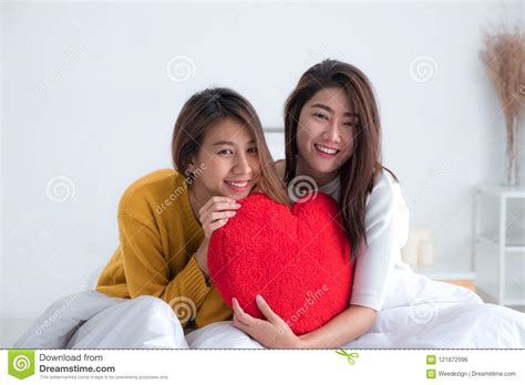 asia lesbian lgbt couple holding red heart pillow together