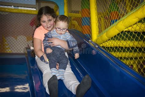 in the playroom on the slide the sister holds her little brother in