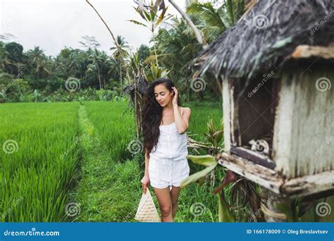 Woman Walking In Rice Fields With Traditional Balinese Straw Hat In