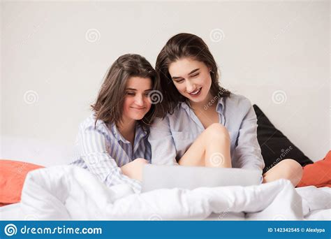 two attractive women with laptop in bed stock image
