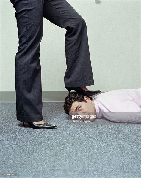 businesswoman placing foot on mans head low section side view photo