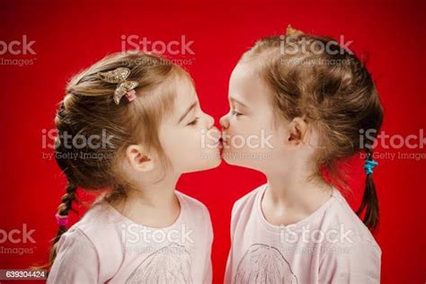 zwei schwestern geben sich gegenseitig einen kuss stockfoto und mehr
