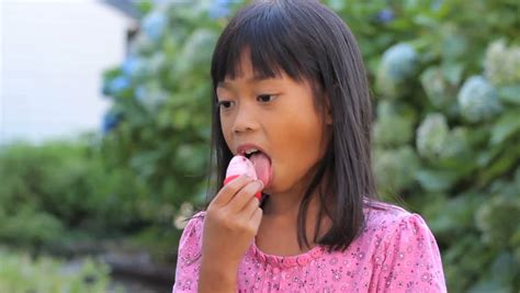 a cute little 6 year old asian girl enjoys licking her