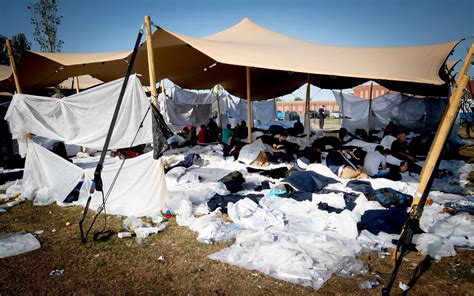 honderden vluchtelingen voor het asielcentrum  ter apel schuilen onder luifels tegen de