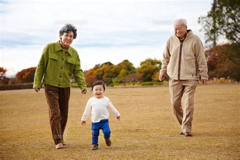 芝生の上でおじいちゃんとおばあちゃんと散歩する孫[10132105514]の写真素材・イラスト素材｜アマナイメージズ