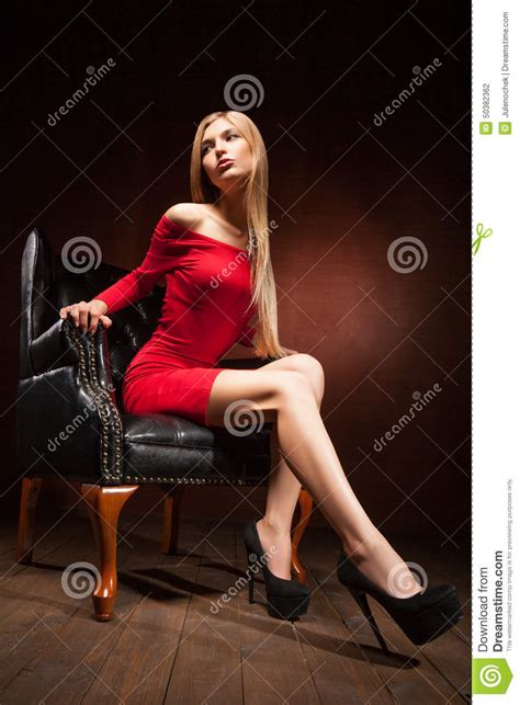 beautiful woman wearing red dress sitting on black chair