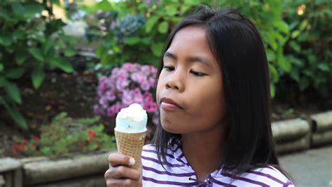 a cute 9 year old asian girl enjoys a delicious ice cream cone during the summer stock footage