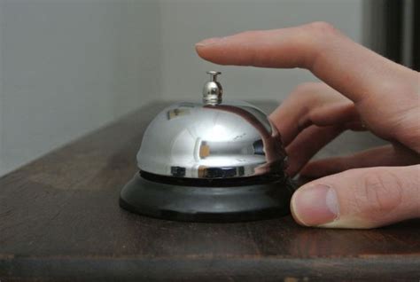 close    persons hand   silver bell   wooden table