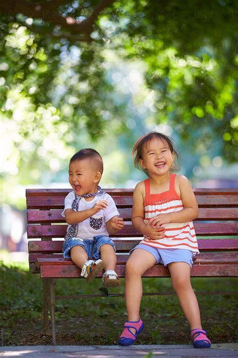 lovely kids sitting   bench   park  stocksy