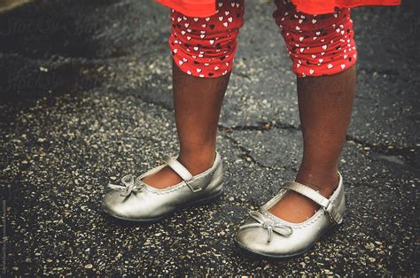 african american girl s feet wearing silver shinning shoes by stocksy