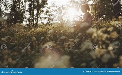Beautiful Asian Girl Sitting On Flowering Meadow In Park Or Forest And