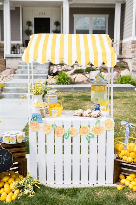 an outdoor lemonade stand is set up on the lawn with yellow and white