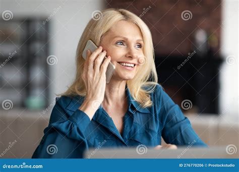 Happy Mature Woman Talking On Cellphone Working Distantly From Home