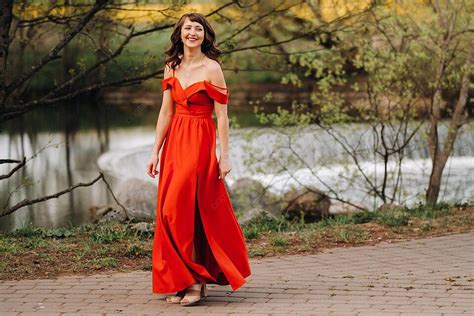 at sunset in the park a girl dons a long red dress by the lake photo