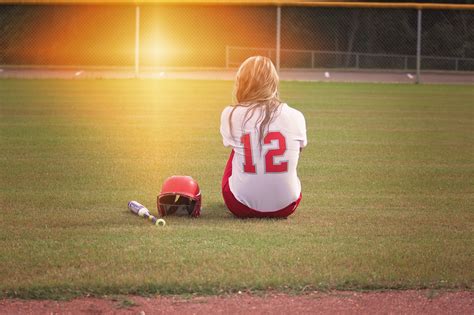 Free Photo Female Baseball Player Sitting On Grass Field Beside Helmet