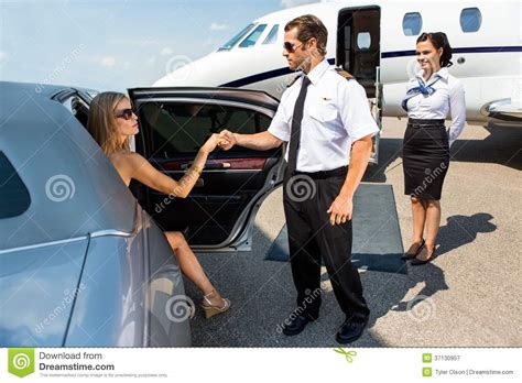 Pilot Helping Elegant Woman Stepping Out Of Car Stock