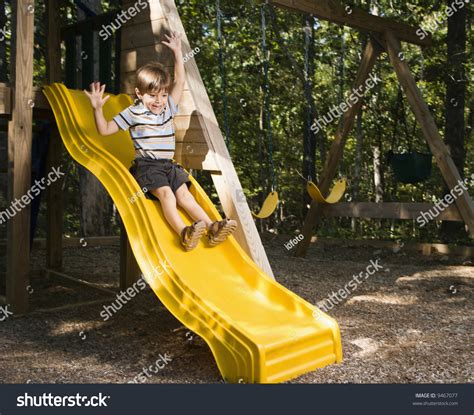hispanic boy sliding  outdoor   arms raised  head stock photo
