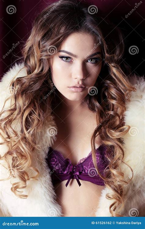 de schitterende vrouw met lang krullend haar draagt luxueuze lingerie en bontjas stock foto