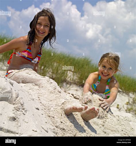 zwei mädchen 11 und 7 jahre spielen im sand am strand stockfotografie