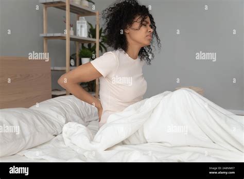 unhappy african american woman rubbing stiff back muscles after