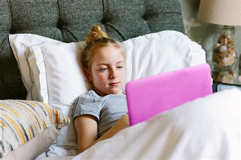 Preteen Girl Streaming A Tv Programme On Her Laptop In Bed By Stocksy