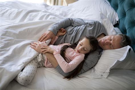 Father And Daughter Sleeping Together On Bed In Bedroom Stock Image