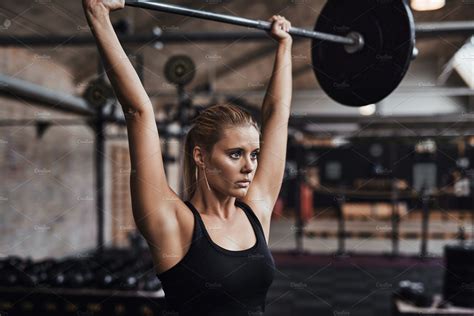 young woman lifting weights   head   gym   active sports recreation