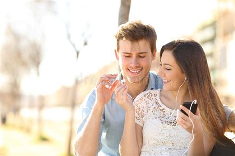 Two Friends Sharing A Smartphone On A Park Bench Stock Image Image Of