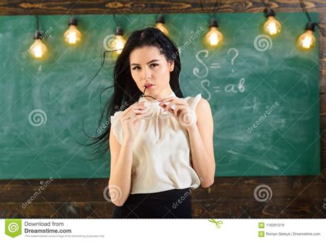 woman with long hair in white blouse stands in classroom