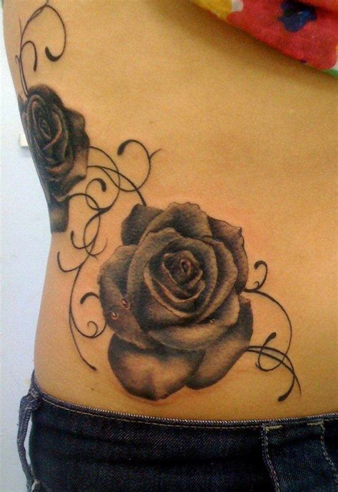 a black rose tattoo on the side of a woman s stomach with swirls around it