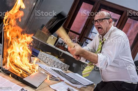 Mature Adult Businessman Smashing Laptop On Fire With Hammer Stock