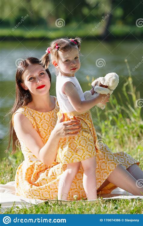 mother and daughter sitting on a white blanket girl