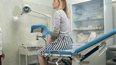 Gynecologist Asking Female Patient To Sit On Gynecological Chair For