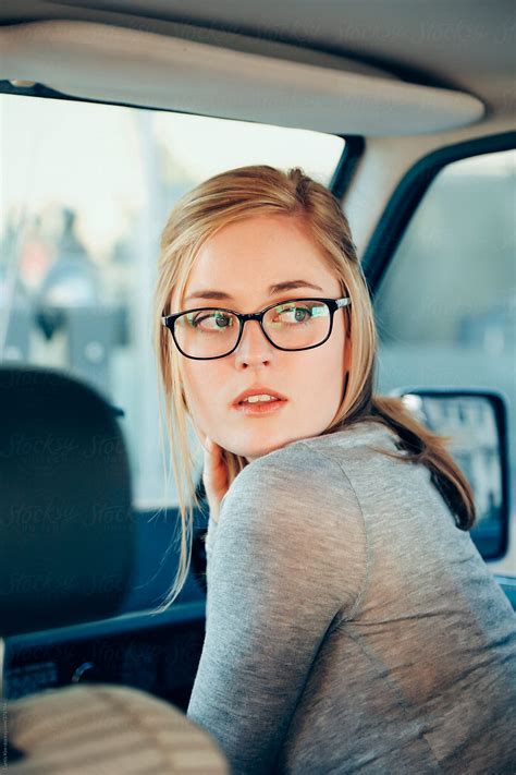 beautiful blonde girl looking back wearing glasses inside a car by