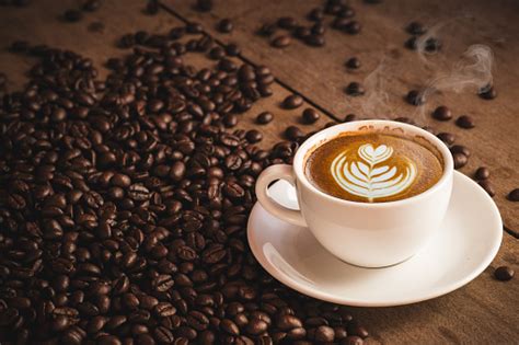koffiebonen en heet cofee cup met latte art on houten achtergrond