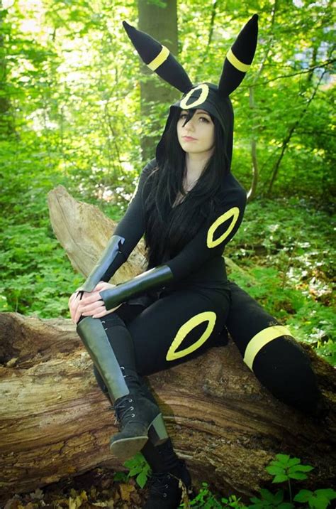 A Woman Sitting On Top Of A Log In The Woods Wearing Black And Yellow