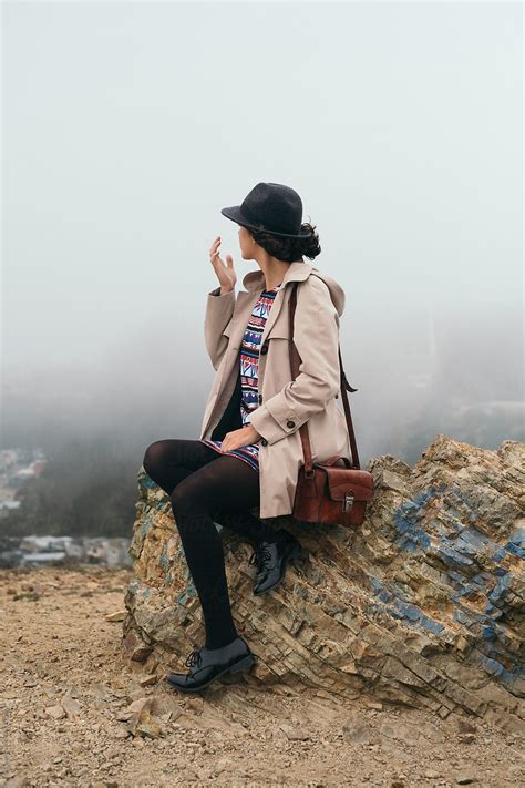Wind Haired Brunette In Hat Sitting On Rock On Top Of San Francisco