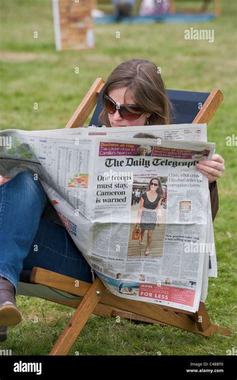 Young Woman Reading The Daily Telegraph Newspaper Sitting In Deckchair