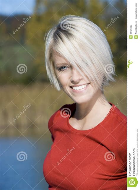beautiful blond woman smiling by a lake royalty free stock