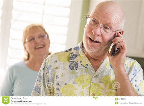 Senior Adult Husband On Cell Phone With Wife Behind Stock