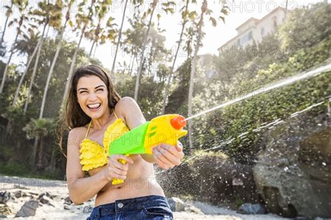 caucasian couple playing with squirt guns on beach photo12 tetra