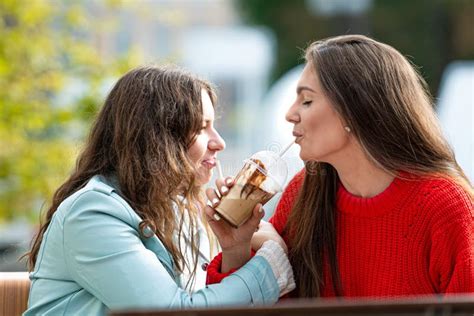Two Milenial Girlfriend Spend Free Time In Outdoor Cafe With Cocktails