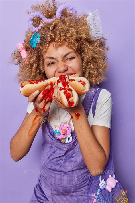 cheat meal concept vertical shot of pregnant curly woman bites tasty