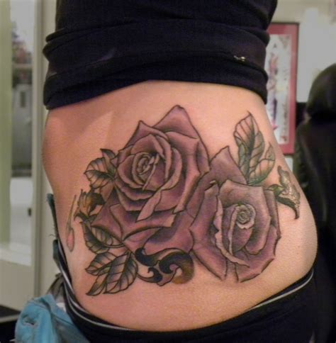 a woman s stomach with tattoos on it and roses in the middle of her belly