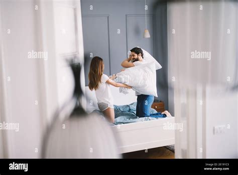 Young Smiling Cute Couple Fighting With Pillows In The Bedroom Stock