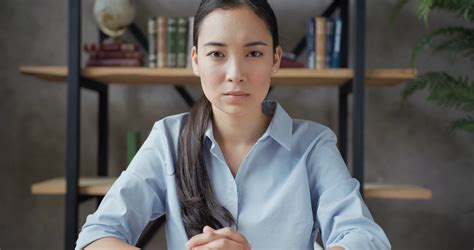 close up portrait of serious asian woman teacher sitting at the table